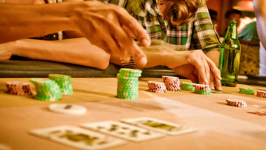 close up of chips and hands on a poker table